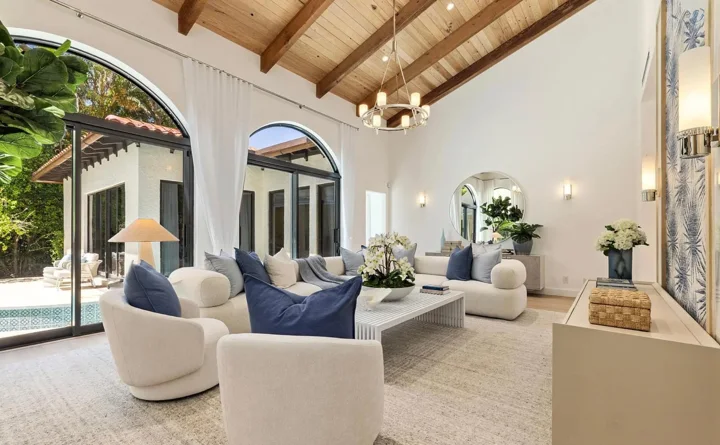 Grand estate living room with tall arched windows, exposed wood beams, and pristine wall finishes