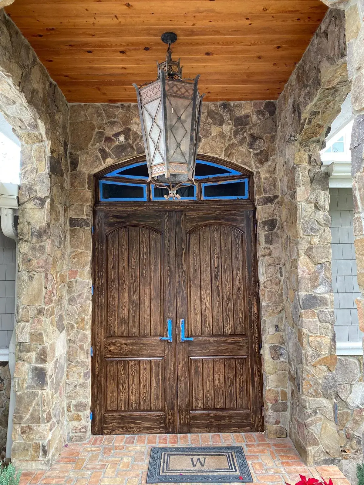 Wooden entry doors framed by stone and a timber porch ceiling