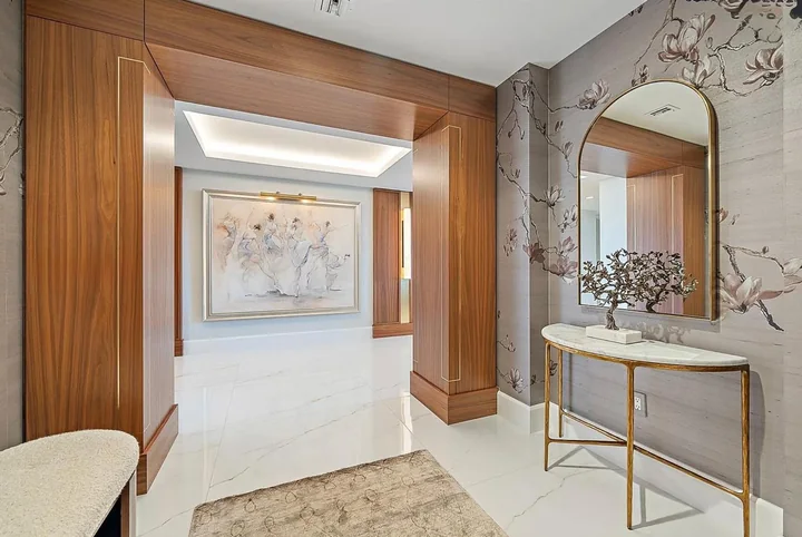 Warm wood doorway framing a paneled hall beside a decorative wall