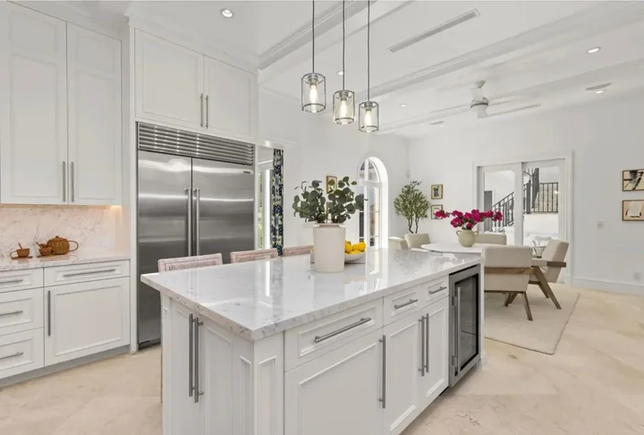 White kitchen cabinetry with a marble island and pendant lights